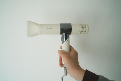 a person holding a hair dryer in their hand at Hostel JAZ in Tokyo