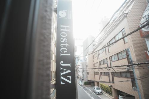 a sign for a building on a city street at Hostel JAZ in Tokyo