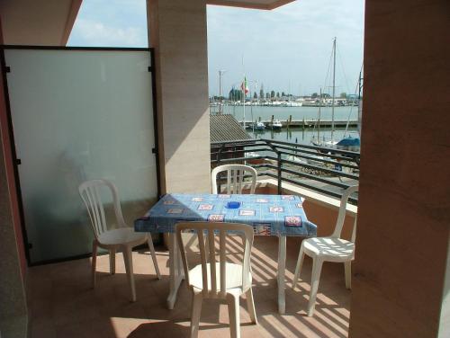 einen Tisch und Stühle auf einem Balkon mit Yachthafen in der Unterkunft Residence Magnolia in Grado