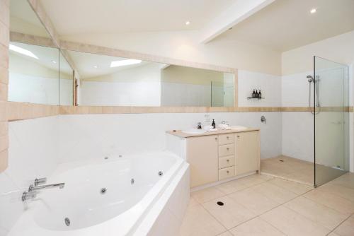 a bathroom with a tub and a sink and a shower at Pet-Friendly Waterfront Hideaway in Noosa Heads