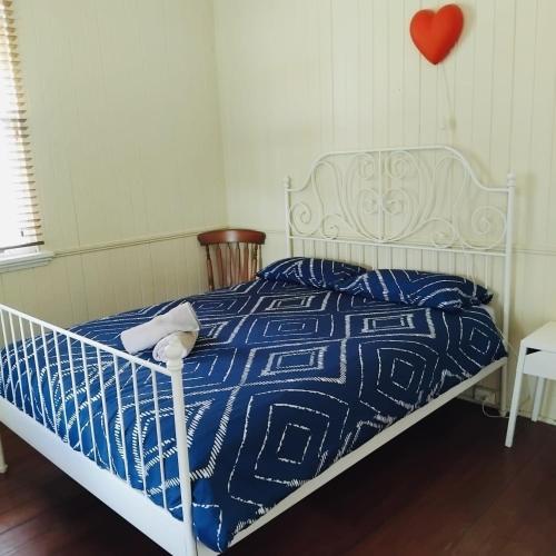 a bed with a blue and white blanket and a red heart at Beautiful house with city views in Brisbane