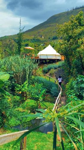 a person walking down a path in a garden with a tent at QuillaGlamping in Píllaro