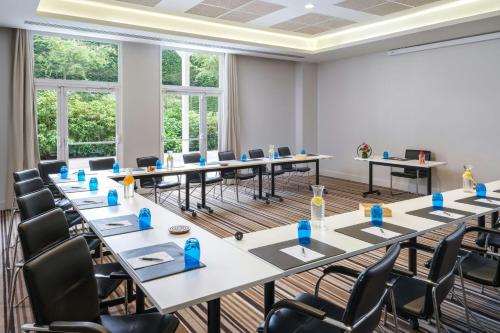 a room with tables and chairs in a room with windows at Renaissance Paris Hippodrome de St. Cloud Hotel in Rueil-Malmaison