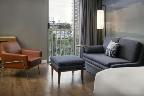a hotel room with a bed and a couch and a chair at Courtyard by Marriott Long Beach Downtown in Long Beach