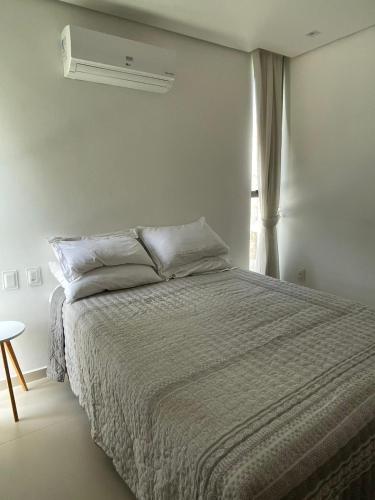 a white bedroom with a bed and a window at Loft Charmoso com Rooftop no Vila das Dunas in Flecheiras