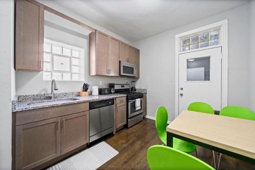 a kitchen with wooden cabinets and a table with green chairs at Cozy Woodlawn Retreat 2 in Chicago