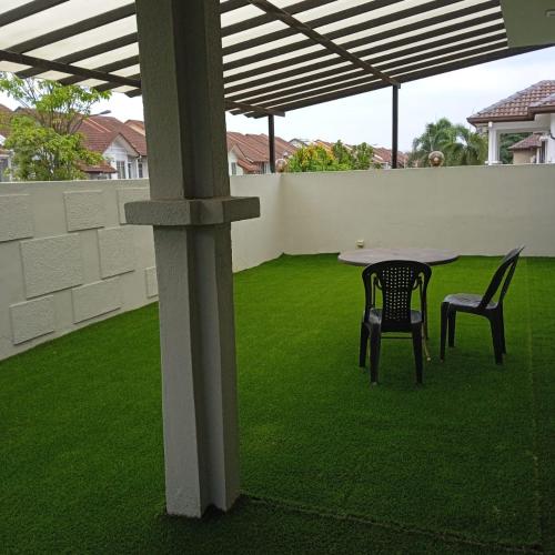 a patio with two chairs and a table on a lawn at Putra Heights Subang Jaya Paradise Property No 1 in Subang Jaya