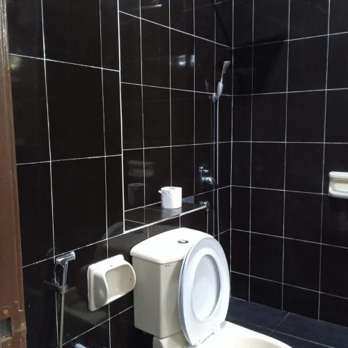 a bathroom with a toilet and a black tiled wall at Putra Heights Subang Jaya Paradise Property No 1 in Subang Jaya