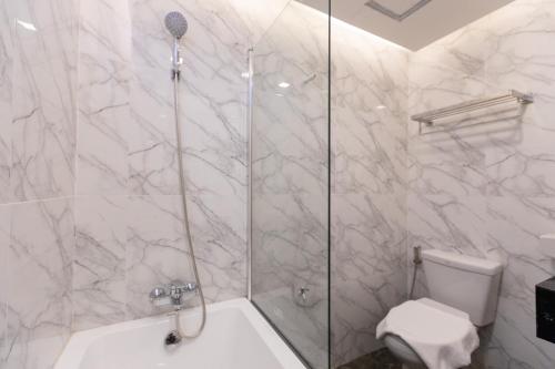 a bathroom with a shower with a toilet and a sink at Airbus Hotel At Phawana Station in Bangkok