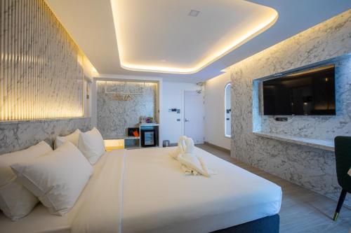 a bedroom with a white bed with a tv on the wall at Airbus Hotel At Phawana Station in Bangkok