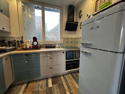 une cuisine avec un réfrigérateur blanc et une fenêtre dans l'établissement Charmante Maison 2 Chambres, Jardin et WIFI à La Roche-Posay - FR-1-541-158, à La Roche-Posay
