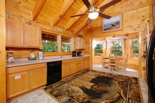 a kitchen with wooden cabinets and a ceiling fan at Arcade game, hottub, dog friendly 2 bedroom log cabin in Gatlinburg near Ober and the national park! in Gatlinburg