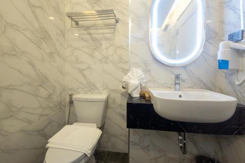 a white bathroom with a toilet and a sink at Airbus Hotel At Phawana Station in Bangkok