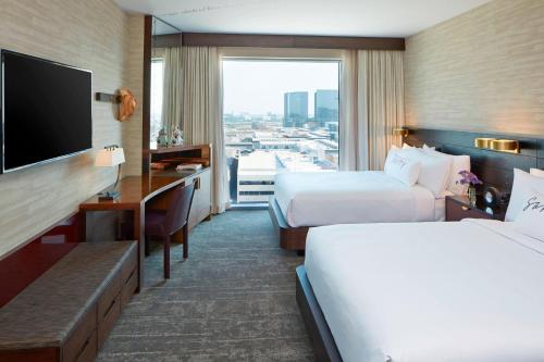 a hotel room with two beds and a flat screen tv at Renaissance Dallas at Plano Legacy West Hotel in Plano