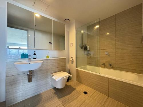 a bathroom with a sink and a toilet and a tub at Luxury Meriton Suites Retreat in Brisbane