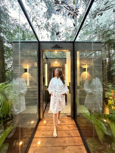 a woman walking out of a glass house at Bosque Veneza in Nova Veneza