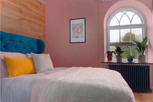 a bedroom with a bed with a blue headboard and a window at Old Chapel Llanfrynach in Brecon