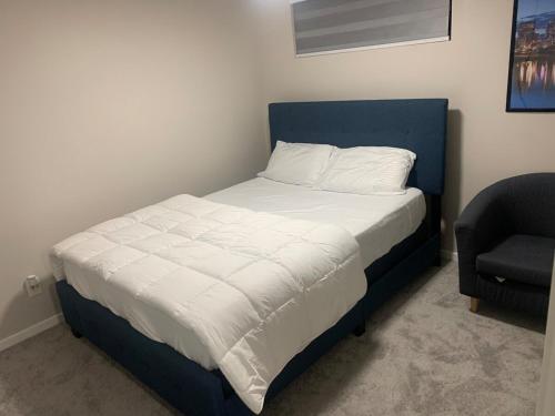 ein Schlafzimmer mit einem Bett mit einem blauen Kopfteil und einem Stuhl in der Unterkunft The Cozy Oasis in Winnipeg