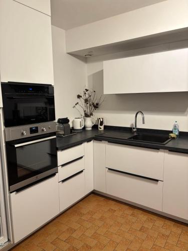 une cuisine avec des armoires blanches et un four à plaques de cuisson dans l'établissement Maison les dunes proche plage, à Quiberon