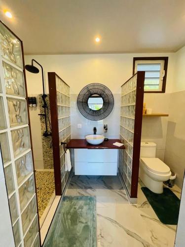 a bathroom with a sink and a toilet and a mirror at Fare Moorea in Moorea