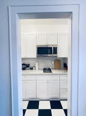 a kitchen with white cabinets and a black and white checkered floor at Studio Downtownhighfallskitchentvunitypet in Rochester