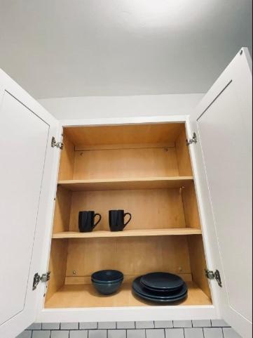 a cupboard with two plates and two mugs at Studio Downtownhighfallskitchentvunitypet in Rochester