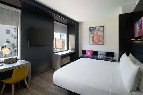 a bedroom with a large white bed and a desk at Aloft Sarasota in Sarasota