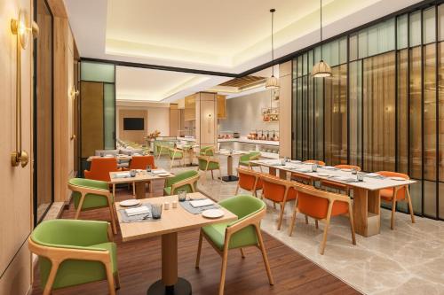a restaurant with wooden tables and green chairs at Hilton Garden Inn Surat City Centre in Surat