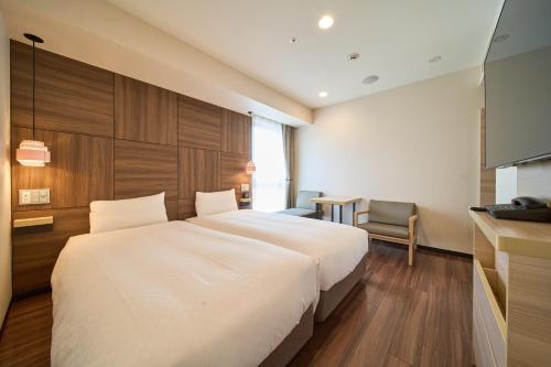 a bedroom with a large white bed and a chair at Via Inn Abeno Tennoji in Osaka