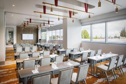 a dining room with tables and chairs and large windows at Hotel Nia, Autograph Collection in Menlo Park
