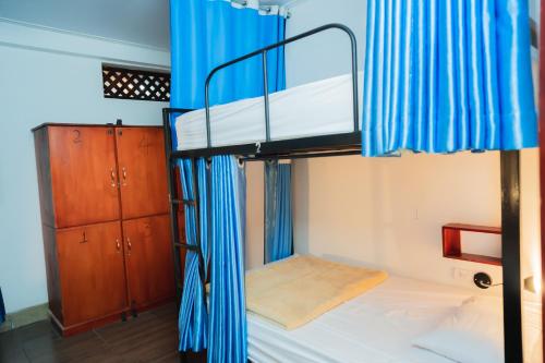 a bunk bed with blue curtains in a room at Vientiane Ruby Riverside Hotel in Vientiane