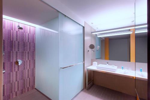 a bathroom with a shower and a sink and a mirror at Aloft Kuala Lumpur Sentral in Kuala Lumpur