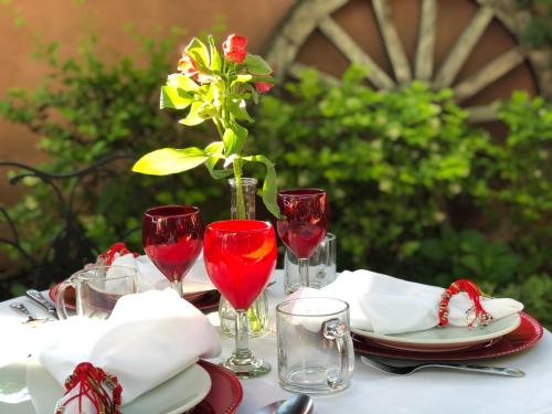 a table with red wine glasses and a vase with a flower at Casa Culinaria - The Gourmet Inn in Santa Fe