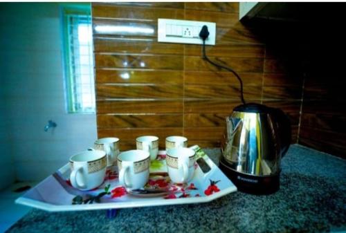a tray of coffee cups on a counter next to a tea kettle at Garuda Grand in Tirupati