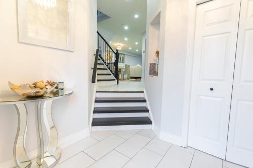a hallway with a staircase with white walls and white floors at An Ideal Home Away From Home in London