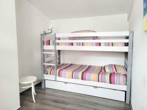 Cette chambre comprend 2 lits superposés et une chaise. dans l'établissement Maison 4 pièces à étage - Proche mer - Patio, BBQ - Parking - FR-1-705-94, aux Mathes
