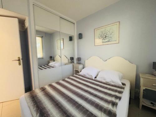 - une chambre avec un lit et un grand miroir dans l'établissement ARGELES SUR MER - Appartement T2 en rez de jardin - Vue mer - FR-1-309-493, à Argelès-sur-Mer