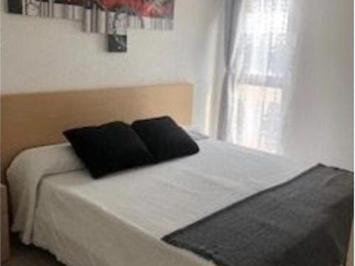 ein Bett mit zwei schwarzen Kissen darauf in einem Schlafzimmer in der Unterkunft VILLAS COSETTE Apartamento Neptuno 417 / Confort total en la Costa Brava: WiFi, piscina y aire acondicionado incluidos! - ES-209-90 in Platja  d'Aro
