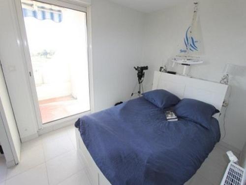 une chambre avec un lit avec des draps bleus et une fenêtre dans l'établissement Appartement climatisé 2 pièces cabine, 6 couchages, Port Camargue - FR-1-731-115, au Grau-du-Roi