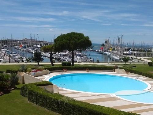 une grande piscine à côté d'un port de plaisance avec des bateaux dans l'établissement Appartement 2 pièces avec piscine pour 4 personnes - FR-1-731-116, au Grau-du-Roi