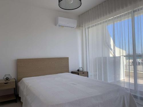 une chambre avec un lit blanc et une grande fenêtre dans l'établissement Bel Appartement 4 Pers avec Clim & Parking, Port Camargue - FR-1-731-119, au Grau-du-Roi