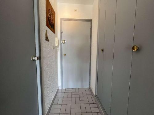 un couloir avec une porte blanche et du carrelage. dans l'établissement Studio au Cap d'Agde avec parking, piscine proche du port - FR-1-249-420, au Cap d'Agde