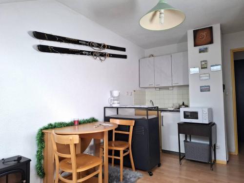 une cuisine avec une table et une cuisine avec une cuisinière dans l'établissement Studio proche pistes avec parking – 2 personnes - FR-1-592-83, à Font-Romeu