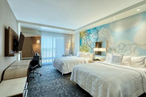 a hotel room with two beds and a tv at Courtyard by Marriott North Brunswick in North Brunswick