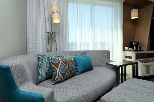 a living room with a gray couch with blue pillows at Courtyard by Marriott North Brunswick in North Brunswick