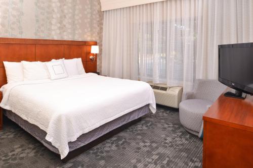 a hotel room with a bed and a flat screen tv at Courtyard Pittsburgh Monroeville in Monroeville