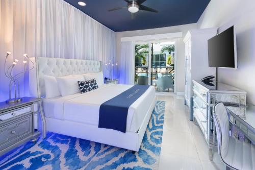 a bedroom with a white bed and a television at The Saint Hotel Key West, Autograph Collection, Adult Only in Key West