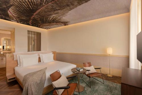a hotel room with a bed and a table and chairs at The Ivens, Autograph Collection in Lisbon