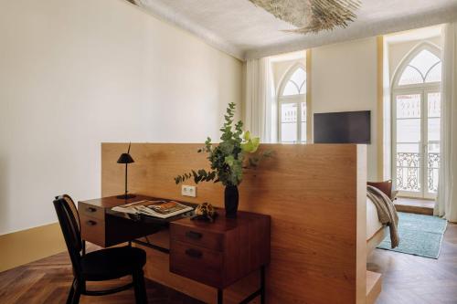a room with a desk and a table with a chair at The Ivens, Autograph Collection in Lisbon