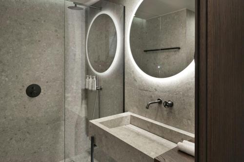 a bathroom with a shower with a sink and two mirrors at MonAsty, Thessaloniki, Autograph Collection in Thessaloniki